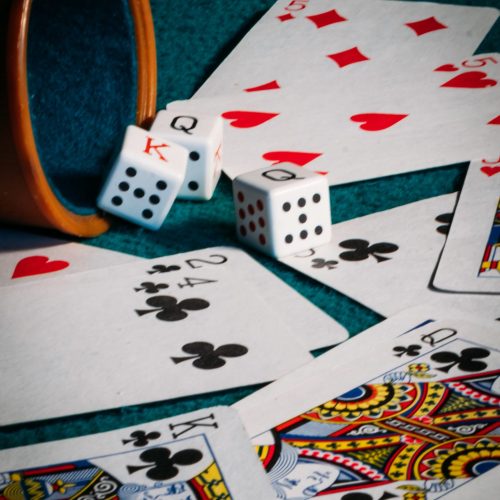 A vertical shot of poker dices, a cup, and cards on a green mat